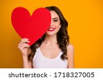 Photo of pretty cheerful lady hold big paper heart postcard hiding half facial expression 14 february romance date present wear white casual singlet isolated yellow color background