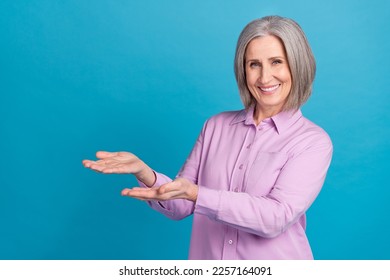 Photo of pretty cheerful lady wear trendy clothes two arm demonstrate novelty proposition empty space isolated on blue color background - Powered by Shutterstock