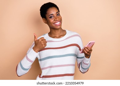 Photo Of Pretty Confident Unisex Person Wear Sweater Reading Gadget Thumb Up Isolated Beige Color Background