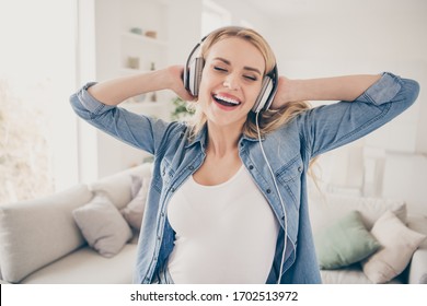 Photo Of Pretty Crazy Blond Lady Rejoicing House Party Dancing Near Couch Stay Home Listen Cool Earphones Hold Hands On Ears Eyes Closed Overjoyed Quarantine Time Living Room Indoors