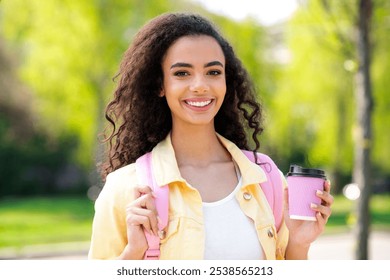 Photo of pretty curly hair good mood girl drink coffee paper cup pink backpack wear yellow jacket walk outside urban city park - Powered by Shutterstock