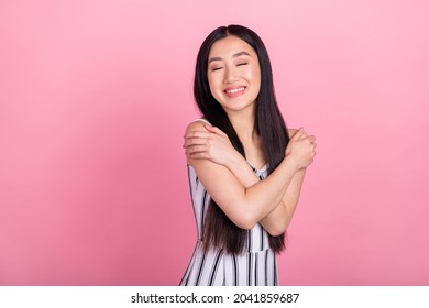 Photo of pretty dreamy young woman dressed white clothes smiling hugging herself closed eyes isolated pink color background