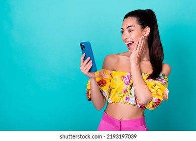 Photo Of Pretty Excited Girl Dressed Cropped Top Reading Modern Gadget Arm Cheek Empty Space Isolated Teal Color Background