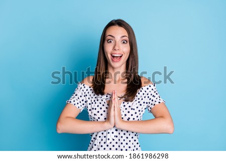 Photo of pretty excited girl open mouth hold hands plead wear dotted blouse isolated blue color background