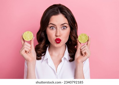 Photo of pretty flirty young girl dressed white top rising two lime slices pouted lips isolated pink color background