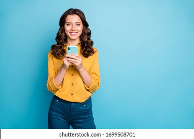 Photo Of Pretty Freelancer Lady Holding Telephone Hands Reading New Positive Comments Instagram Blog Post Wear Yellow Shirt Trousers Isolated Blue Color Background