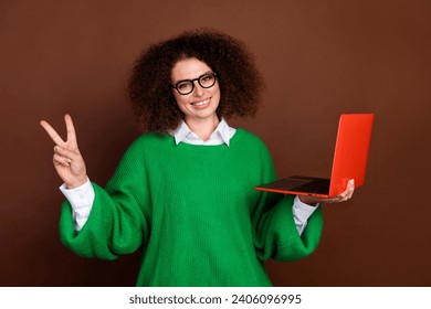 Photo of pretty friendly recruiter girl hold laptop demonstrate v-sign isolated on brown color background