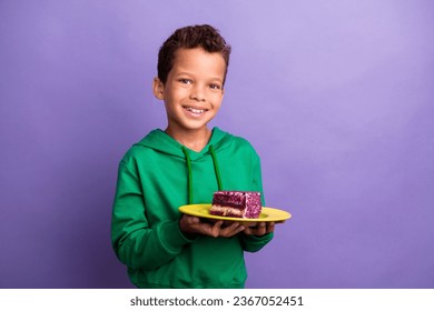 Photo of pretty funky little boy dressed green hoodie holding cake piece plate empty space isolated purple color background - Powered by Shutterstock