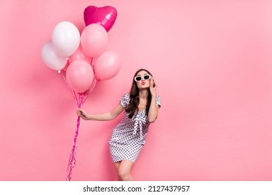 Photo of pretty funny lady dressed dotted dress dark eyewear holding air balls sending kiss isolated pink color background