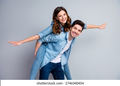 Photo pretty funny lady handsome guy couple carry piggyback meet adventures playful mood spread arms like wings wear casual denim shirts outfit isolated grey color background