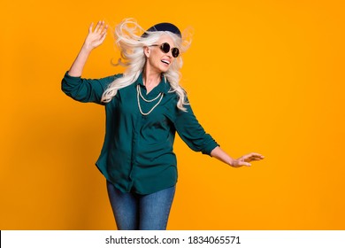 Photo Of Pretty Funny White Hair Grandma Lady Walk Street Enjoy Season Breeze Hairstyle Fly Wear Green Shirt Sun Specs Necklace Jeans Retro Hat Isolated Bright Yellow Color Background