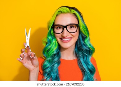 Photo of pretty funny young bright lady dressed orange t-shirt glasses holding hands arms scissors smiling isolated yellow color background