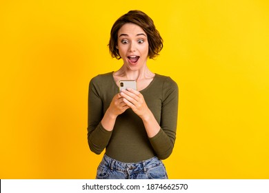 Photo of pretty girl hold smartphone look screen amazed face open mouth wear green shirt isolated vivid yellow color background - Powered by Shutterstock