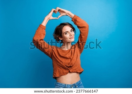 Photo of pretty girlfriend showing heart symbol with her arms under head isolated blue color background