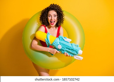 Photo Of Pretty Good Mood Curly Lady Travel Have Best Trip Entertainment Pool Party Hold Bouy Water Gun Wear Trendy Outfit Isolated Yellow Color Background