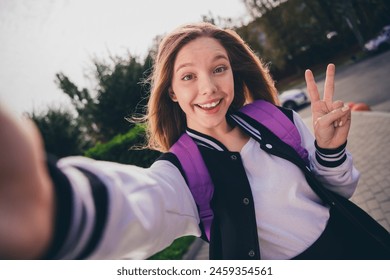 Photo of pretty good mood girl wear school uniform rucksack showing v-sign tacking selfie outside urban city park - Powered by Shutterstock