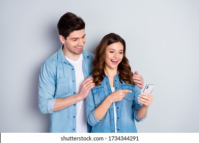 Photo pretty lady handsome guy boyfriend girlfriend couple showing telephone funny picture direct finger screen wear casual denim shirts outfit isolated grey color background