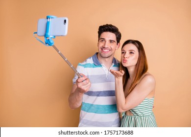 Photo of pretty lady handsome guy couple hold selfie stick photographing send air kisses popular family bloggers wear casual summer clothes isolated pastel beige color background