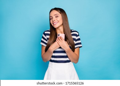 Photo Of Pretty Lady Hold Telephone Hands Reading Love Letter Email Smart Phone Close To Chest Dreamy Mood Wear Striped T-shirt White Skirt Isolated Blue Color Background