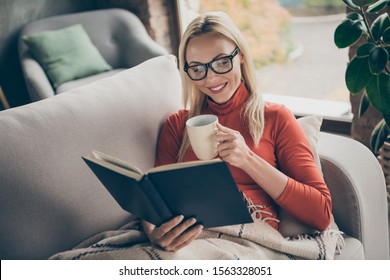 Photo Of Pretty Lady Holding Favorite Book Novel Hands Enjoy Saturday Morning Drink Hot Beverage Lying Comfy Couch Covered Blanket Wear Specs Casual Outfit Flat Indoors