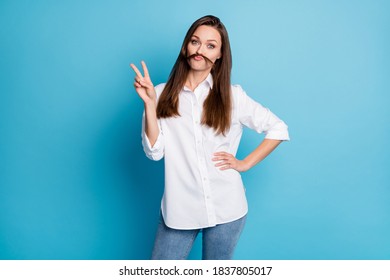 Photo of pretty lady playing long hairstyle curl making mustache showing v-sign wear shirt jeans isolated blue color background