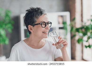 Photo of pretty retired woman look empty space drink water wear white outfit home flat rest relax spend free spare time living room indoor - Powered by Shutterstock