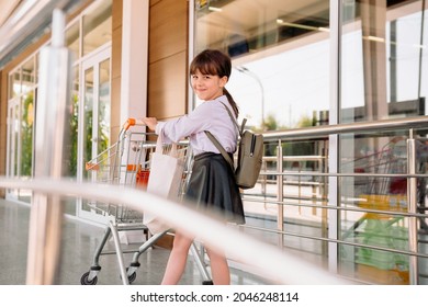 The Photo Of A Pretty School Aged Girl With A Backpack On The Back And Smiling Facial Expression Heading To The Supermarket And Carries The Grocery Cart.