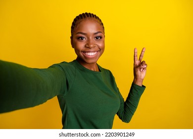 Photo Of Pretty Shiny Young Lady Dressed Green Shirt Tacking Selfie Showing V-sign Isolated Yellow Color Background