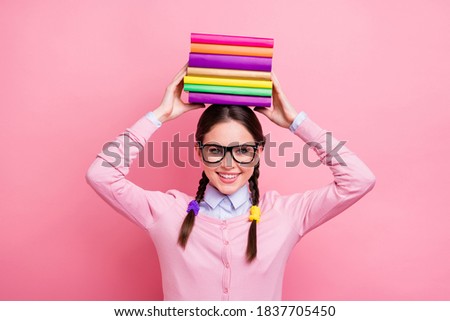 Photo of pretty student lady hold literature pile on head good mood like reading preparing examination college university wear shirt pullover specs isolated pink color background
