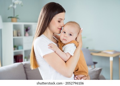 Photo Of Pretty Sweet Lady Wear White T-shirt Smiling Holding Arms Hands Kissing Baby Inside Indoors House Room