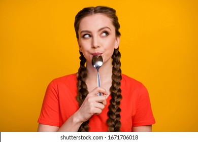 Photo Of Pretty Teenager Lady Hold Metal Spoon In Mouth Desire Dinner Look Dreamy Empty Space Think Of Tasty Food Wear Casual Red T-shirt Isolated Vivid Yellow Color Background