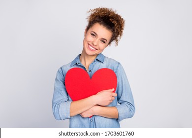 Photo of pretty wavy lady hold hands hugging red paper heart affectionate feelings toothy smile wear casual denim blue shirt isolated grey color background - Powered by Shutterstock