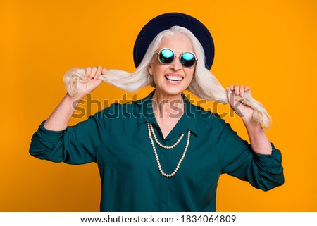 Photo of pretty white hair grandma lady senior party active life cool look hold long curls hands wear green shirt sun specs necklace retro hat isolated bright yellow color background
