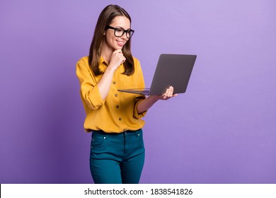 Photo Of Pretty Young Girl Arm Chin Hold Computer Toothy Smile Wear Glasses Yellow Shirt Blue Pants Isolated Violet Color Background