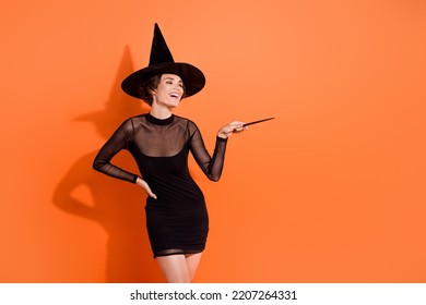 Photo Of Pretty Young Girl Point Magic Wand Harry Potter Character Wear Stylish Black Halloween Witch Garment Isolated On Orange Background