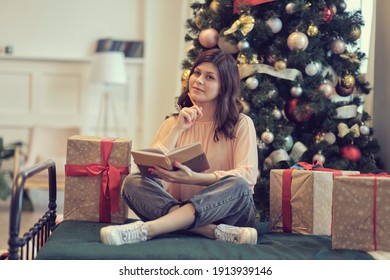 Photo Of Pretty Young Lady Cuddle Paper Book. Christmas Holidays And People Concept Happy Young Woman With Pencil And Notebook Writing In Bed At Home Bedroom