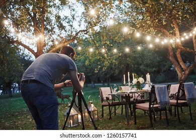 Photo of professional photographer in eyeglasses taking picture of the served table at outside. - Powered by Shutterstock