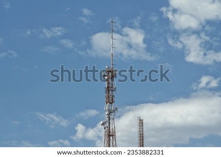 photo of radio and telephony tower, with blue sky and clouds appearing behind