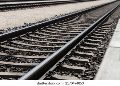 Foto de vías ferroviarias que recorren diagonalmente la imagen con una plataforma parcialmente visible como concepto de dirección tristeza de viaje y soledad