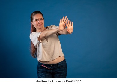 Photo Reaction. Young Woman Putting On A Brake With Her Hands. Woman Dodging An Awkward Situation. Woman Saying No With Both Hands. Young Woman Pushing Someone