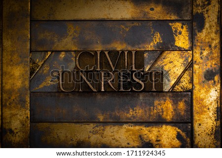 Photo of real authentic typeset letters forming Civil Unrest text on vintage textured grunge copper and gold background