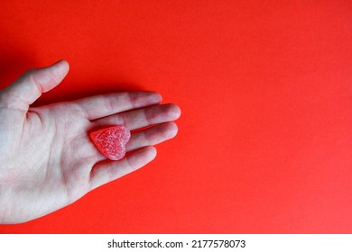 Photo Of Red Jelly Candy Heart In Hand Of Woman On Red Background