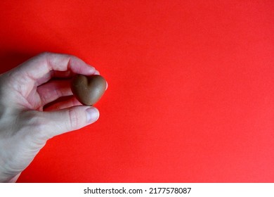 Photo Of Red Jelly Candy Heart In Hand Of Woman On Red Background