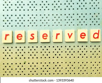 Photo Red Of Letters Spelt Reserved On Blue And Yelow Peg Board With Copy Space For Text For Cards