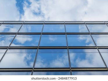 It's the photo of reflection of blue sky and clouds in windows of skyscraper. It is close up view of glass window wall of building in midday. - Powered by Shutterstock