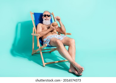 Photo of relaxing sweet pensioner shirtless smiling sitting beach chair drinking alcohol empty space isolated teal color background