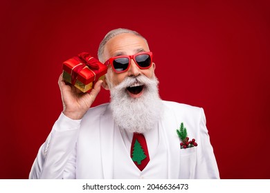 Photo of retired amazed dreamy man look empty space hold present box christmas isolated on red color background