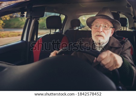 Photo of retired grandfather drive highway hold steering wheel wear brown coat headwear eyeglasses inside car