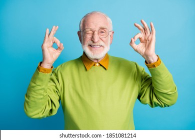 Photo Of Retired Old Man Raise Two Hands Show Okey Wink Eye Wear Eyewear Green Pullover Isolated Blue Color Background