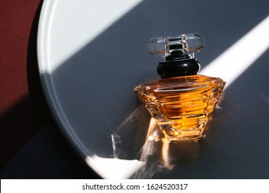 Photo of a rich luxury perfume cologne water on wonderful color geometric background with sunlight and harsh shadows